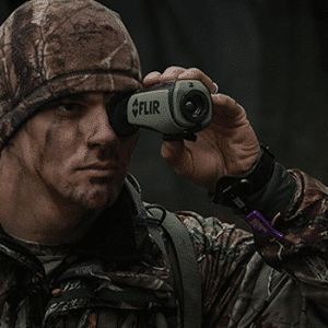Man in camouflage seen looking through a Teledyne FLIR Scout II thermal monocular.