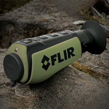 Front side angle view of a Teledyne FLIR Scout II thermal monocular sitting on a rock.