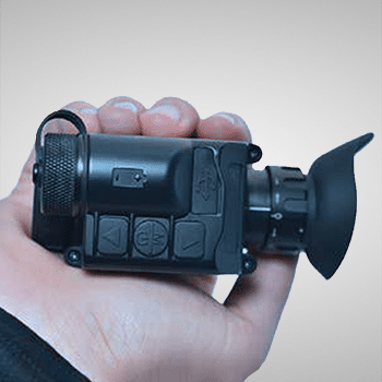 Photo showing a AGM StingIR handheld thermal monocular fitting in the palm of a hand.