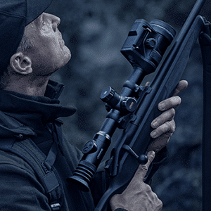 Man shown holding a bolt-action rifle with a Pulsar Thermion 2 LRF Pro thermal riflescope attached.