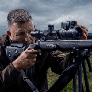 Man shown looking through a Thermion 2 LRF XL50 mounted to a bolt-action rifle.